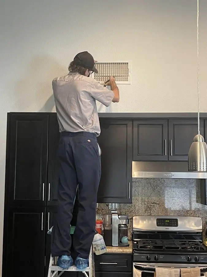 Technician inspecting an air vent during HVAC service in Lemoore Station